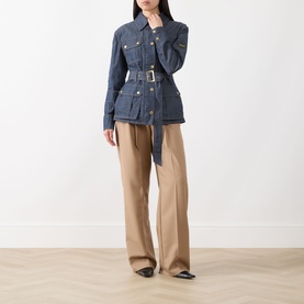 Model wearing Barbour International International Denim Trench Jacket in dark blue with gold-tone hardware and belt, styled with wide-leg camel