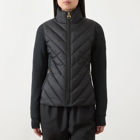 Model wearing Barbour International black quilted jacket with chevron pattern, gold zip, and stretch knit sleeves