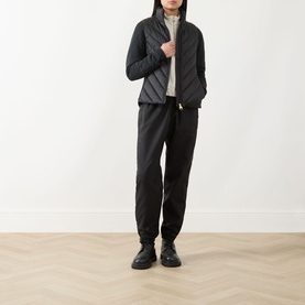Model wearing Barbour International black quilted jacket with zip front, styled with black joggers and black lace-up shoes.