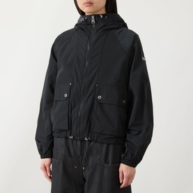 Model wearing Barbour International black hooded windbreaker jacket with front pockets and elasticated hem, styled with matching black trousers.