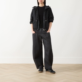 Model wearing Barbour International black polyamide hooded jacket with black tee, wide-leg dark jeans and black trainers.