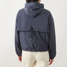 Model wearing Barbour International Maizy Showerproof Jacket in Odyssey, rear view showing back yoke, hood, and elasticated cuffs, styled with cream
