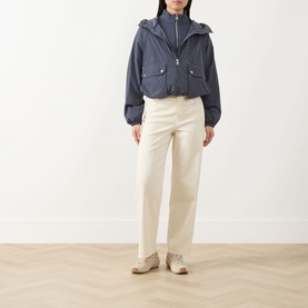 Model wearing Barbour International Maizy Showerproof Jacket in Odyssey, styled with cream wide-leg trousers and beige trainers.
