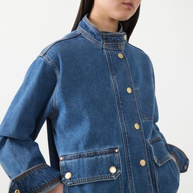 Model wearing Barbour International Nikki Biker Denim Jacket in Denim Blue, showing stand collar, gold snap buttons, contrast stitching and flap