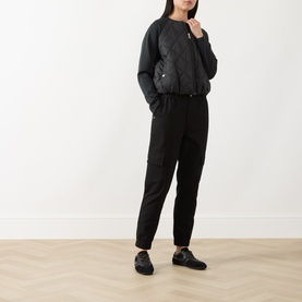 Model wearing Barbour International Seren Quilted Bomber Jacket in black, styled with black tapered trousers and black loafers.