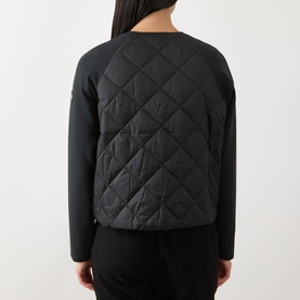 Model wearing Barbour International Seren Quilted Bomber Jacket in black, showing rear view with quilted back panel and long jersey sleeves.
