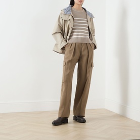 Model wearing Barbour Hinton Striped Knitted Sweater in Light Sand Stripe, styled with khaki cargo trousers, beige jacket and black loafers.