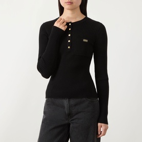Model wearing Barbour International Kyla Logo Rib-Knit Sweater in black with gold button half placket, crew neck, styled with dark grey jeans.