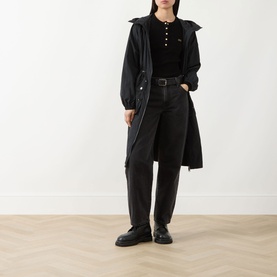 Model wearing Barbour International Kyla Logo Rib-Knit Sweater in black, styled with long black coat, wide-leg trousers and chunky loafers.
