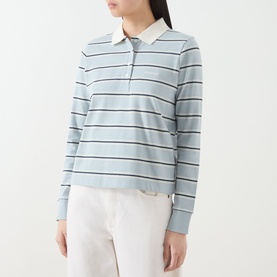 Model wearing Barbour Ashwell Logo Striped Polo Shirt in Celestial Blue Stripe, long sleeves, ribbed cuffs, polo collar, paired with white trousers.