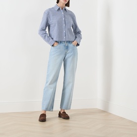 Model wearing Barbour Ashwell Gingham Shirt in blue multi gingham with light-wash wide-leg jeans and brown loafers.