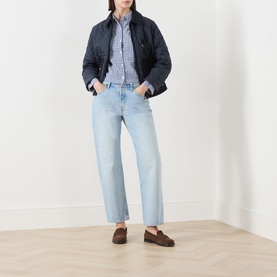 Model wearing Barbour Ashwell Gingham Shirt in Multi Gingham with navy quilted jacket, light blue straight-leg jeans and brown loafers.