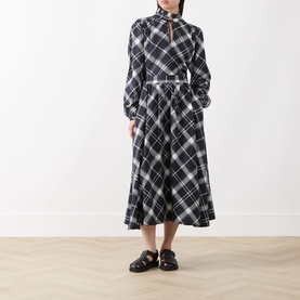 Model wearing Barbour Bailton Tartan Blouse in Dark Navy/White Check with ruffle collar, styled with a white belt, midi skirt and black mules.