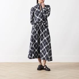 Model wearing Barbour Bailton Tartan Skirt in Dark Navy/White Check, midi-length flared silhouette, styled with matching tartan top and black sandals