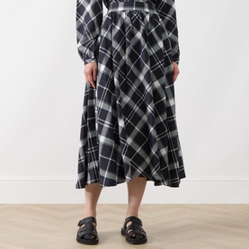 Model wearing Barbour Bailton Tartan Skirt in Dark Navy/White Check, midi-length flared silhouette, paired with black chunky sandals