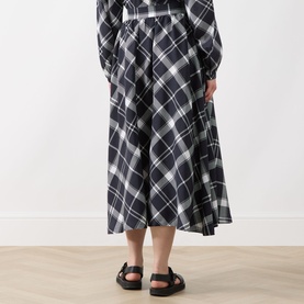 Model wearing Barbour Bailton Tartan Skirt in Dark Navy/White Check, midi-length flared silhouette, styled with matching top and black slides