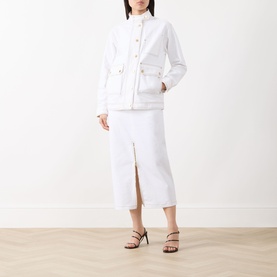 Model wearing Barbour International Kyla Denim Skirt in Denim White, midi length with front zip split, styled with a white jacket and black heeled