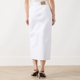 Model wearing Barbour International Kyla Denim Skirt in Denim White, midi length, high-rise with gold logo badge, paired with black heels