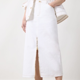 Model wearing Barbour International Kyla Denim Skirt in Denim White, midi length with front zip split, styled with white jacket and bag.