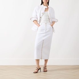 Model wearing Barbour International Kyla Denim Skirt in Denim White, midi length with front zip split, styled with white jacket and black heeled