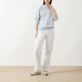 Model wearing Barbour International Pearl Blue cotton sweatshirt with white straight-leg trousers and beige trainers.