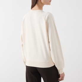 Model wearing Barbour Sweat Top in Ecru, rear view, relaxed crew neck style with raglan sleeves, paired with dark trousers