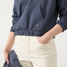 Model wearing Barbour International sweat in Odyssey blue, cropped hem with elasticated waistband and kangaroo pocket, styled with cream trousers.