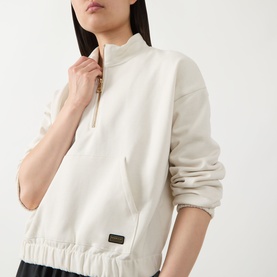 Model wearing Barbour International Light Stone cotton half-zip sweatshirt with ribbed hem, mock neck, and gold-tone zip detail