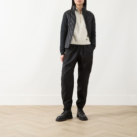 Model wearing Barbour International Light Stone cotton sweat, styled with quilted gilet, black joggers and chunky boots