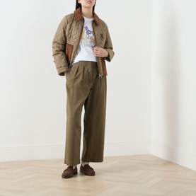 Model wearing Barbour Fawley Dogs Logo T-Shirt in white with khaki wide-leg trousers, quilted jacket, and brown loafers.