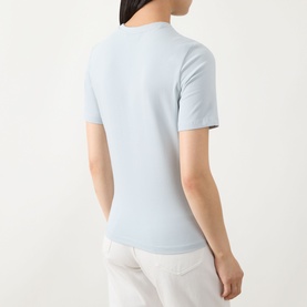 Model wearing Barbour International Pearl Blue fitted short-sleeve T-shirt, rear view, styled with white trousers.
