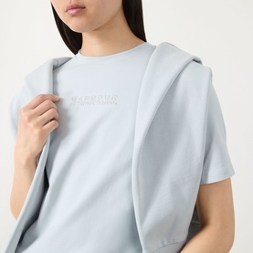 Model wearing Barbour International Pearl Blue cotton T-shirt with tonal embossed logo, styled with a matching zip-up hoodie draped over shoulders.