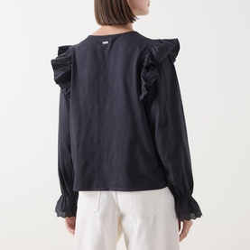Model wearing Barbour Carleen Ruffled Blouse in Dark Navy, rear view showing ruffle shoulders, embroidered cuffs, and long sleeves, styled with white