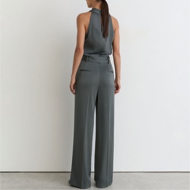 Model wearing Reiss dark grey halterneck wide-leg jumpsuit, shown from the back with a deep V-back and fluid drape
