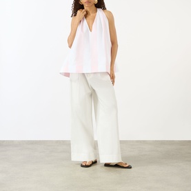Model wearing Jacquemus shirt in jacquard big stripes light pink and white, styled with wide-leg cream trousers and black sandals.