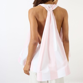 Model wearing Jacquemus shirt in light pink and white jacquard big stripes, backless halter neck design with gathered knot detail, paired with white
