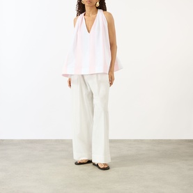 Model wearing Jacquemus cotton shirt in Jacquard Big Stripes Light pink, V-neck halter style, styled with wide-leg white trousers and brown sandals