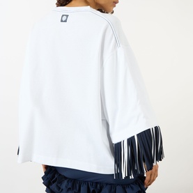Model wearing Jacquemus white cotton T-shirt, back view, with navy fringe hem detail, styled with navy ruffled skirt.