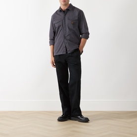 Model wearing Levis Pleated Work Chinos in Mineral Black Twill, slim-leg with front pleats, styled with grey shirt and black chunky shoes.