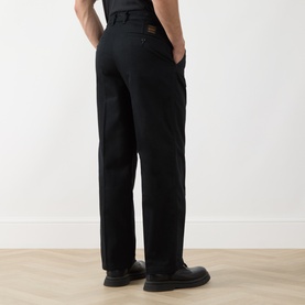 Model wearing Levi's Pleated Work Chinos in Mineral Black Twill, rear view showing jetted back pockets and logo badge, styled with black shoes.