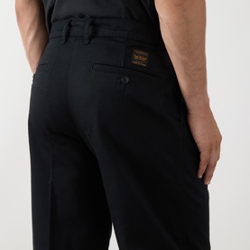 Model wearing Levi's Pleated Work Chinos in Mineral Black Twill, showing rear jetted pockets with button fastenings and logo badge detail.