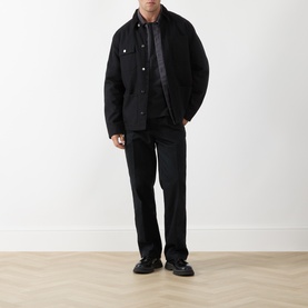 Model wearing Levis Pleated Work Chinos in Mineral Black Twill, slim-leg with front pleats, styled with black jacket and shoes.