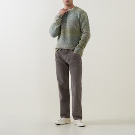 Model wearing Levis 555 Corduroy Relaxed Straight Leg Jeans in Smokey Taupe, styled with a green marl knit sweater and white trainers.