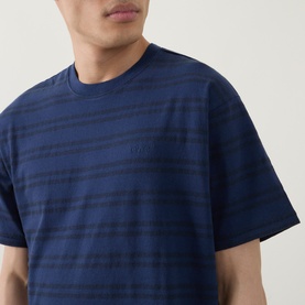 Model wearing Levis Crew Neck T in Grady Chevron Stripe Dress Blues, close-up showing textured stripe pattern and embroidered logo