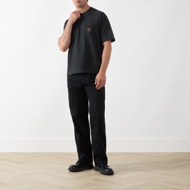 Model wearing Levis Workwear Pocket Logo T-Shirt in Jet Black with crew neck and chest patch pocket, styled with black straight-leg trousers.