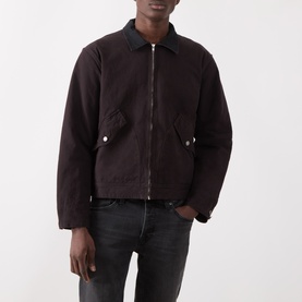 Model wearing Nudie Jeans dark brown cotton casual jacket with zip front, spread collar, and flap pockets, styled with black jeans.