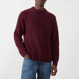 Model wearing Nudie Jeans August Rib Sweater in Burgundy, ribbed wool crew neck with long sleeves, styled with blue jeans.