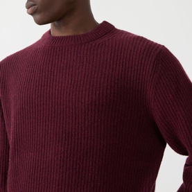 Model wearing Nudie Jeans August Rib Sweater in Burgundy, ribbed wool crew neck knit with long sleeves and ribbed trims.