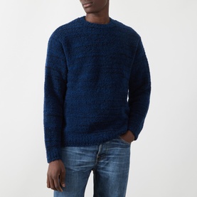 Model wearing Nudie Jeans Gurra Boucle Sweater in R22 Multi, dark navy boucle knit crew neck, styled with blue denim jeans