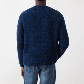 Model wearing Nudie Jeans Gurra Boucle Sweater in R22 Multi, navy boucle knit crew neck, back view, styled with light blue jeans